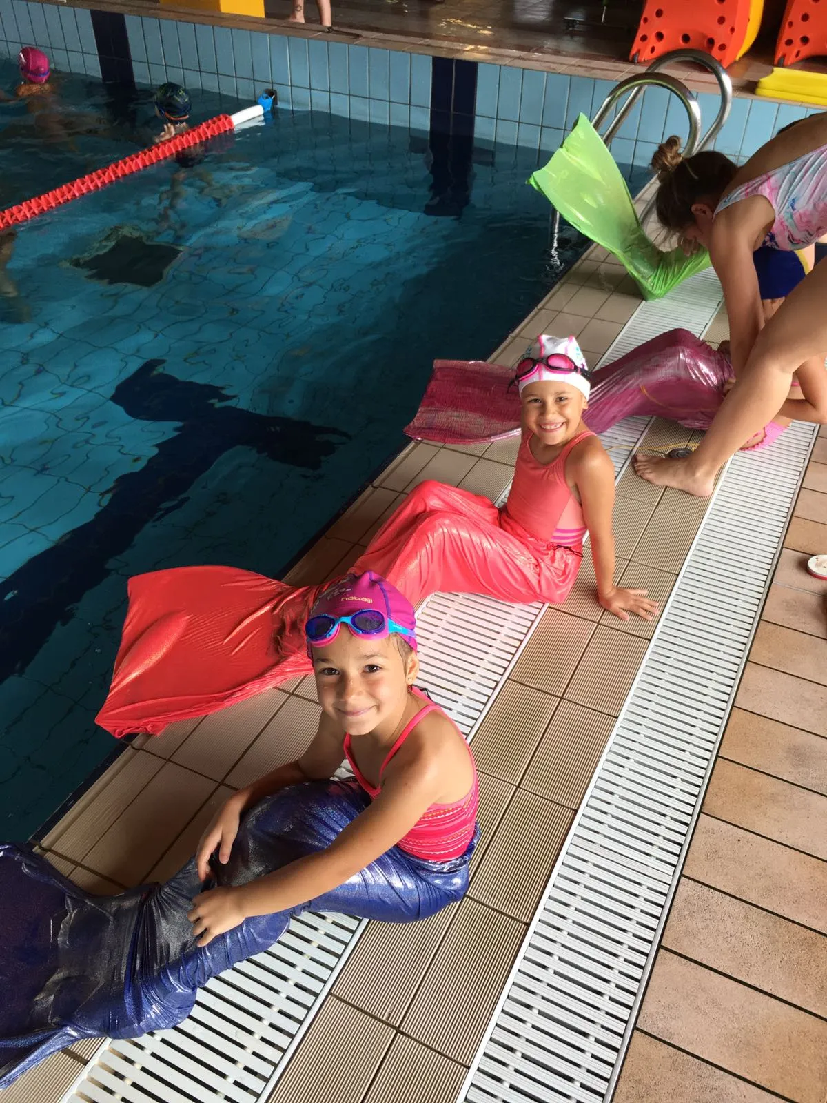 Bambine con la coda da sirena in piscina
